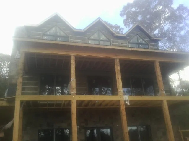 Dormers and porch framing on a large log home under construction — Roof Coating work by our crew in San Francisco