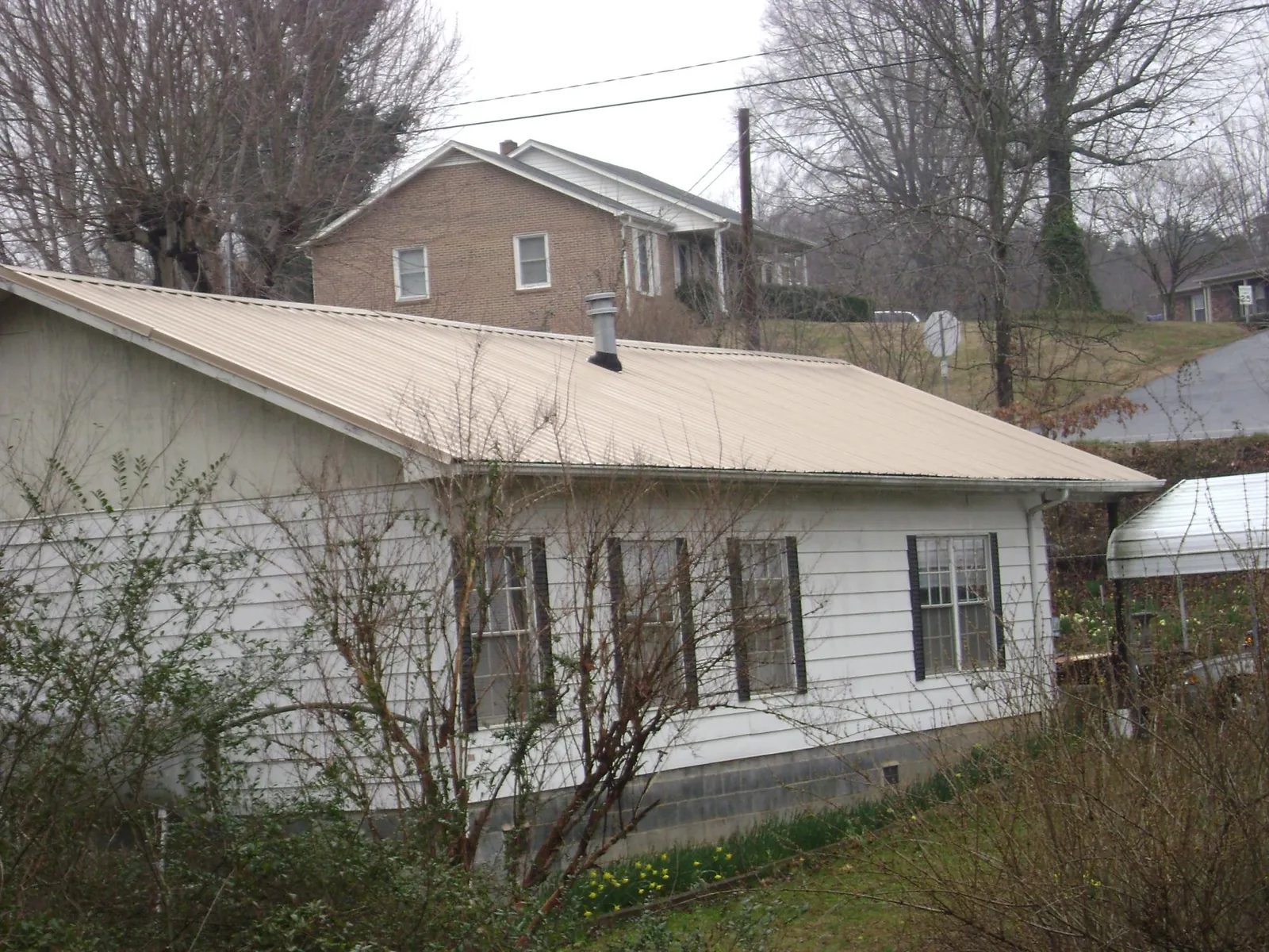 Tan metal roof on a white sided house set into a hillside — Commercial Roofing by Roofing Brothers in San Francisco