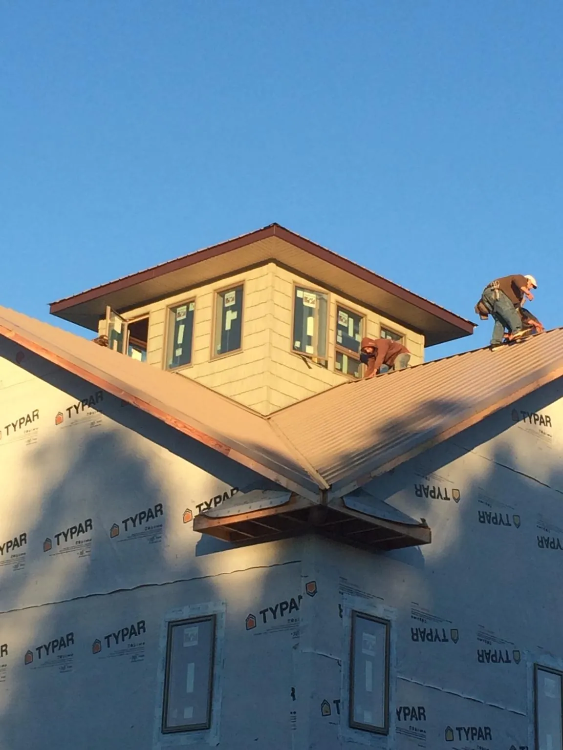 Roofers working around a rooftop cupola on a new metal roof at sunset — Roof Waterproofing in San Francisco by Roofing Brothers